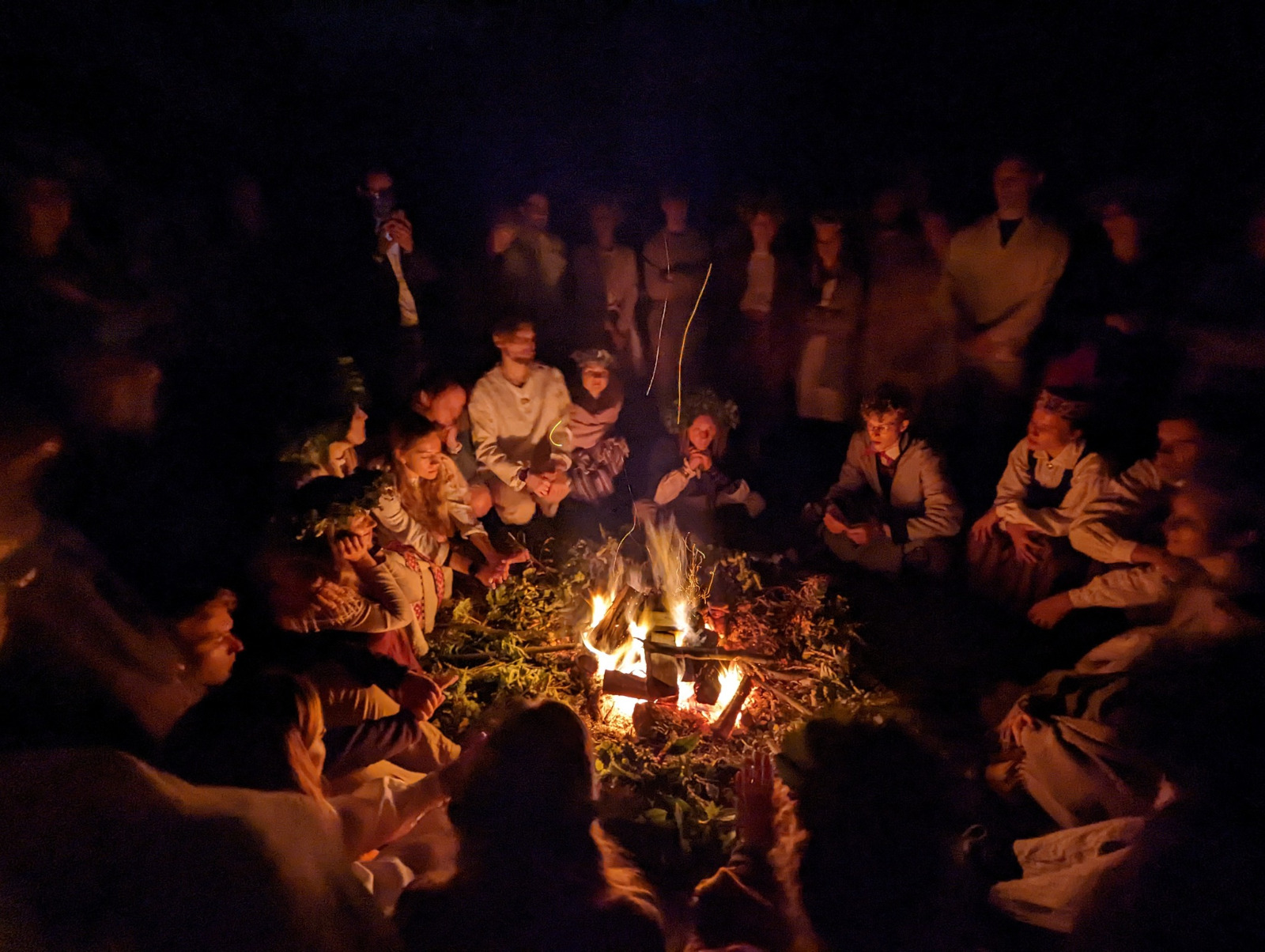 Jovens cantando canções letas ao redor da fogueira, no acampamento 2x2, na Irlanda
